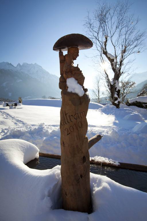 Holzschnitzfigur mit Regenschirm im Schnee