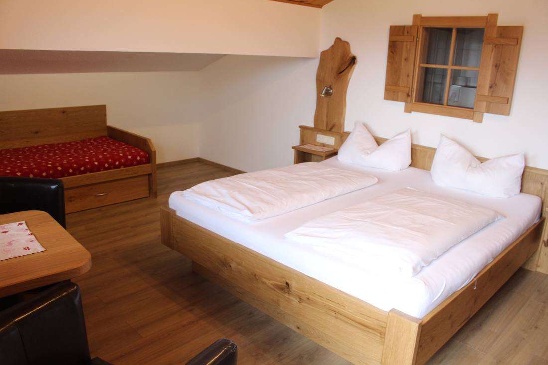 Zimmer mit Holzbett und Ecktisch