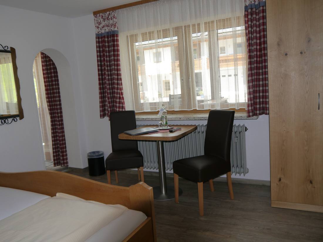 Zimmer mit Tisch und Stühlen am Balkon